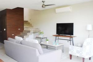 a living room with white furniture and a flat screen tv at New Villa 207 Deluxe , Golf Club, Punta Cala in Nuevo Vallarta 