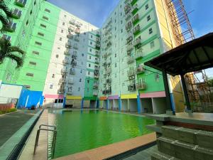 a building with a pool of water in front of it at Comfort 2BR at Bogor Mansion Apartment By Travelio in Bogor