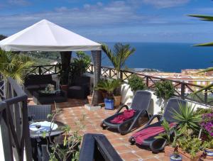 a patio with chairs and an umbrella and the ocean at Holiday home to the street with big kitchen in Icod de los Vinos