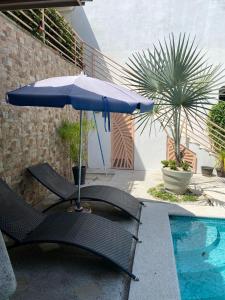 a blue umbrella and chairs next to a swimming pool at Holiday Beach House In Punta Leona - wprivate Pool in Punta Leona