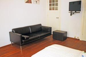 a black leather couch in a living room with a tv at Bed & Breakfast Walenburg in Rotterdam