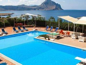 a swimming pool with chairs and a view of the ocean at Casa Mamma Bruna in San Vito lo Capo
