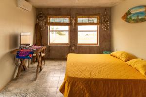a bedroom with a bed and a table and windows at Casa Playa Hermosa in San Blas