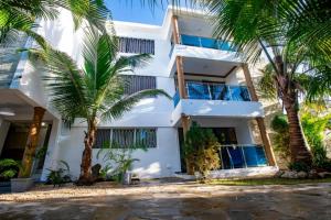 a white building with palm trees in front of it at Fully Equipped 2br Apt-dt5mins To The Beach in Sosúa