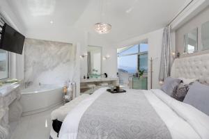a white bedroom with a large bed and a bath tub at Dion Villa Zakynthos Greece One Bedroom Villa with Private Pool no01 in Agios Nikolaos +19 photos