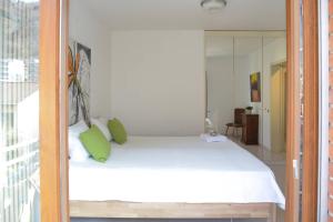 una camera da letto con un letto bianco con cuscini verdi di Casa Melide Seeblick a Melide