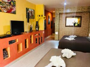 a room with two beds and a flat screen tv at Suite Jacuzzi Room in Stunning Villa Playacar Ii in Playa del Carmen