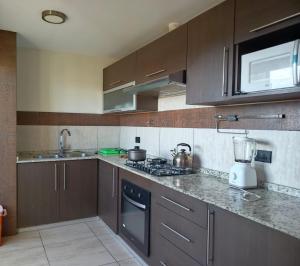 a kitchen with brown cabinets and a stove top oven at Departamento Independencia in Tarija