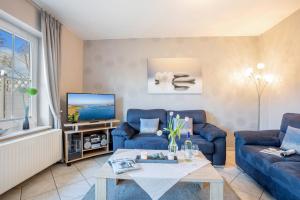a living room with two blue couches and a tv at Ferienhaus Nelke in Fehmarn