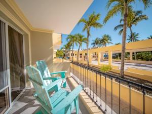 two blue chairs on a balcony with palm trees at Garden Condos 43, Modern Condo In Sosa Center in Sosúa