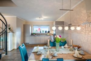a dining room with a table and a kitchen at Bauernhof Lafrenz Wellness - Ferienhaus Ostküste in Fehmarn +8 photos
