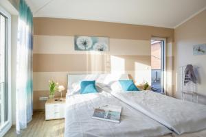 a bedroom with a large white bed with blue pillows at Bauernhof Lafrenz Wellness - Ferienhaus Ostküste in Fehmarn
