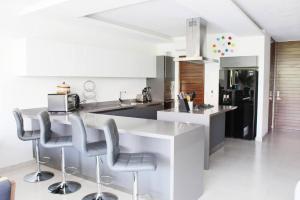 a kitchen with a white counter and stools at New beautiful house in El Tigre, Golf Club, Punta Cala 205 in Nuevo Vallarta 