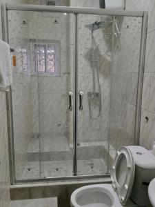 a bathroom with a shower with a toilet and a sink at Blooms Spot Hotel - Super Deluxe in Port Harcourt