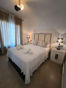 een witte slaapkamer met een groot bed met witte lakens bij Vista bella golf beach in Orihuela +43 foto's