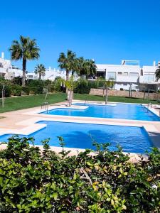 een groot zwembad met palmbomen en een gebouw bij Vista bella golf beach in Orihuela