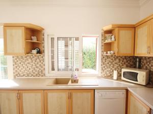 a kitchen with a sink and a microwave at Villa Tanyeli with Private Pool and Terrace in Lapithos