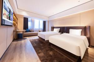 una camera d'albergo con due letti e un divano di Atour X Hotel Wuhan Railway Station West Square a Wuhan