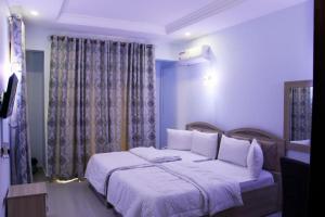 a bedroom with a large bed with white sheets at Msp Residence and Apartments in Abuja