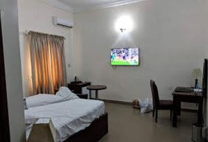 Un dormitorio con una cama, un escritorio y un televisor. en Helena Haven Hotels - Executive, en Port Harcourt