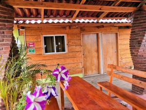eine Holzbank vor einer Hütte mit lila Blumen in der Unterkunft Nice Quadruple Cabin Equipped And Very Central in Zacatlán