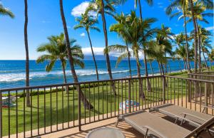 een balkon met stoelen en palmbomen en de oceaan bij Puamana 240-3 in Lahaina