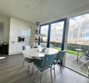 a kitchen and dining room with a table and chairs at 6pers Modern harbor house Jasmijn with fenced garden and lake view in Anjum
