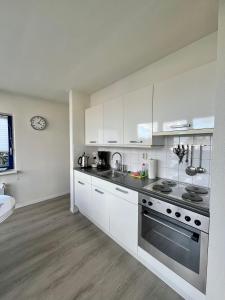 a kitchen with white cabinets and stainless steel appliances at 6pers Modern harbor house Jasmijn with fenced garden and lake view in Anjum +23 photos