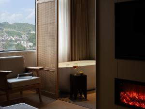 a room with a fireplace and a chair and a window at Yanyu Yunxi Resort Hotel 烟雨云兮酒店 in Fenghuang County