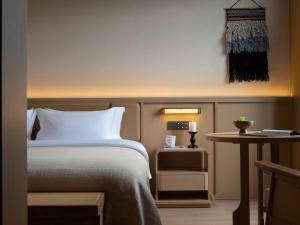 a hotel room with a bed and a table at Yanyu Yunxi Resort Hotel 烟雨云兮酒店 in Fenghuang County