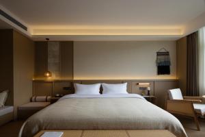 a bedroom with a large bed and a chair at Yanyu Yunxi Resort Hotel 烟雨云兮酒店 in Fenghuang County