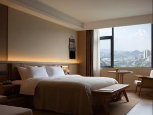 a hotel room with a bed and a large window at Yanyu Yunxi Resort Hotel 烟雨云兮酒店 in Fenghuang County