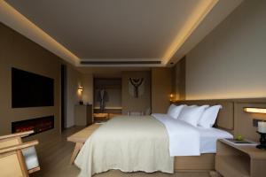 a bedroom with a large white bed and a fireplace at Yanyu Yunxi Resort Hotel 烟雨云兮酒店 in Fenghuang County