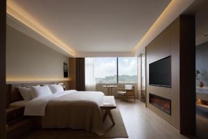 a hotel room with a large bed and a television at Yanyu Yunxi Resort Hotel 烟雨云兮酒店 in Fenghuang County