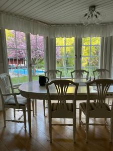 a dining room with a table and chairs and windows at Charming property with private pool in Märsta