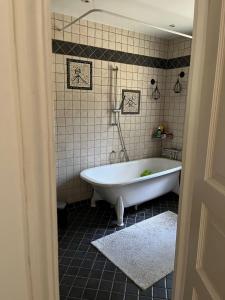 a white tub in a bathroom with a tiled wall at Charming property with private pool in Märsta