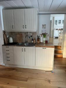 a kitchen with white cabinets and a sink at Charming property with private pool in Märsta
