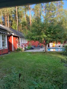 a house with a tree in front of a yard at Charming property with private pool in Märsta