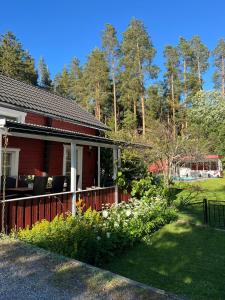 a red house with a fence and some flowers at Charming property with private pool in Märsta