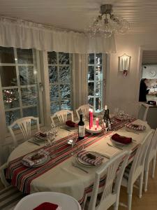 a dining room table with white chairs and wine bottles at Charming property with private pool in Märsta