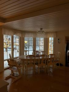 a dining room with a table and chairs and windows at Charming property with private pool in Märsta