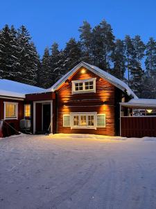 a wooden house with snow on the roof at Charming property with private pool in Märsta