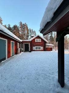 a red barn with snow on the ground at Charming property with private pool in Märsta