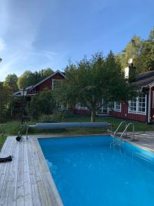 a swimming pool with a wooden deck next to a house at Charming property with private pool in Märsta