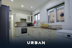 eine weiße Küche mit weißen Schränken und Fenstern in der Unterkunft Spacious 4-Bedroom City Centre Houses, Sleeps 8 With Parking For 3 Cars in Peterborough + 22 Fotos