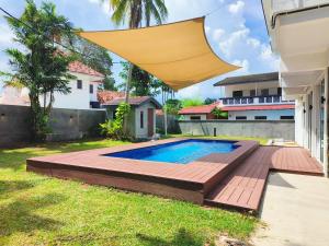 a backyard with a swimming pool and a wooden deck at Port Dikson Beach Side Villa in Port Dickson