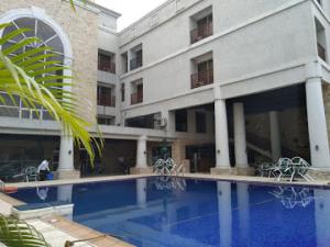 a large building with a swimming pool in front of a building at Full Moon Hotel - Penthouse in Owerri