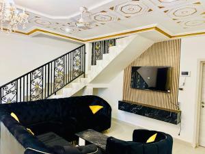 a living room with a black couch and a tv at Villa Amina splendid elegant structure in Ouagadougou
