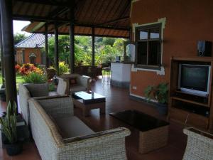 a living room with chairs and a television and a table at Villa Bali Pondok Jepang in Lovina