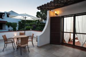 eine Terrasse mit einem Tisch, Stühlen und einem Sonnenschirm in der Unterkunft B&B Canneto Beach in Leporano